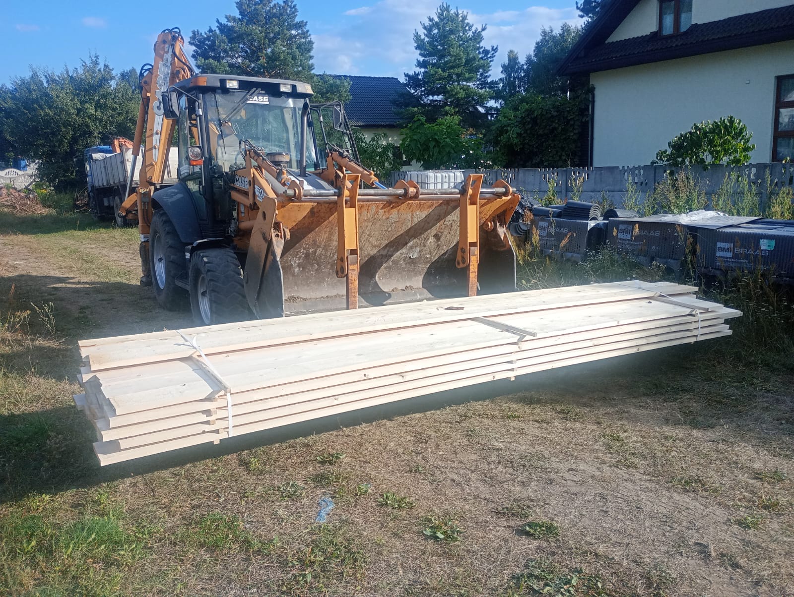 Koparko-ładowarka przy budowie domu - transport materiałów budowlanych i roboty ziemne
