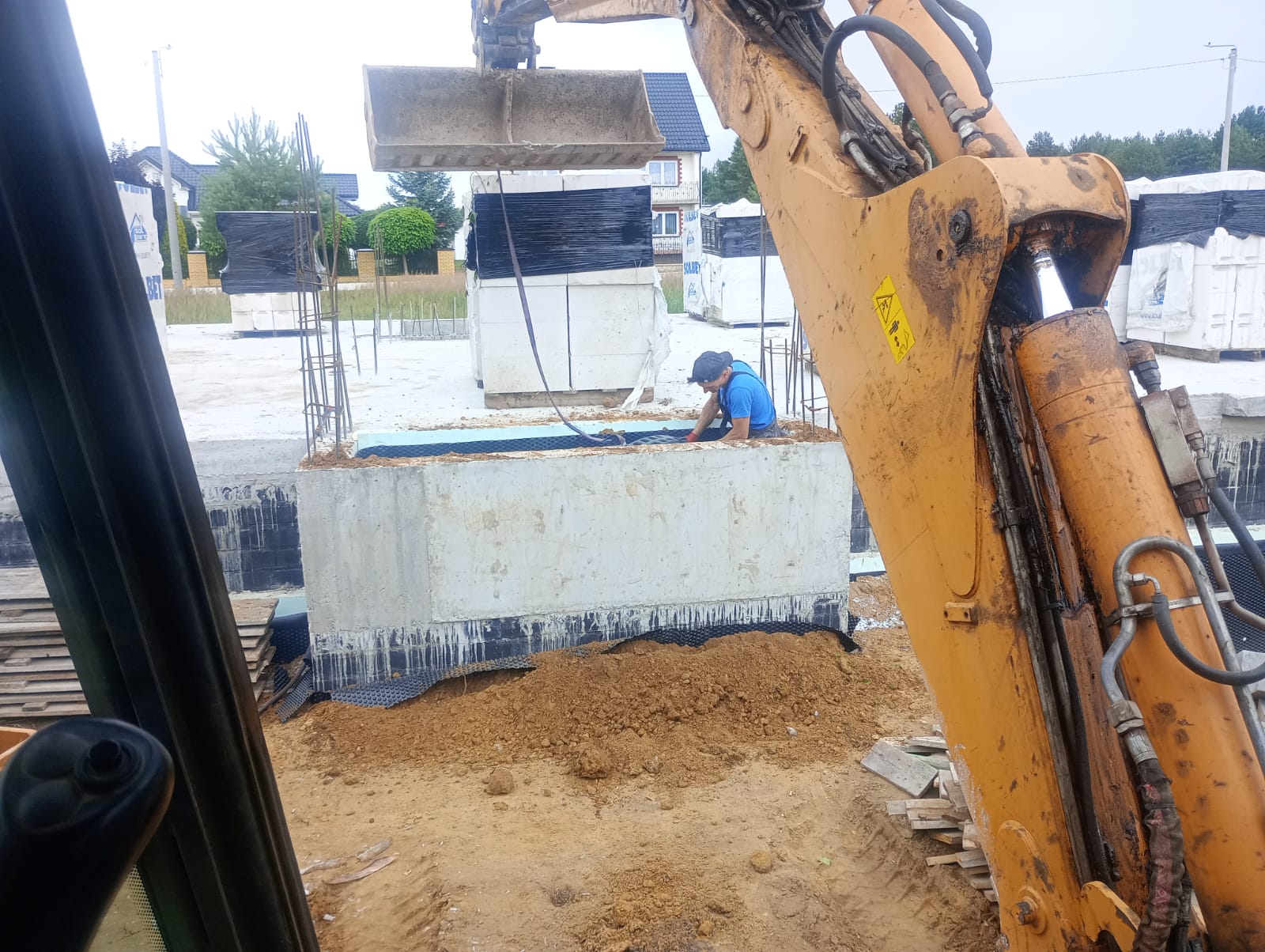 Roboty ziemne na budowie - koparka przy fundamentach i pracach instalacyjnych